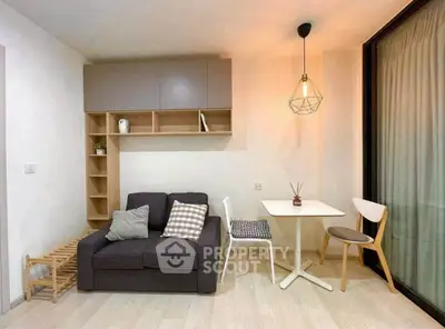 Modern living room with cozy sofa, dining table, and stylish lighting in a compact apartment.