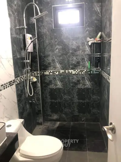 Modern bathroom with sleek black tiles and contemporary shower design.