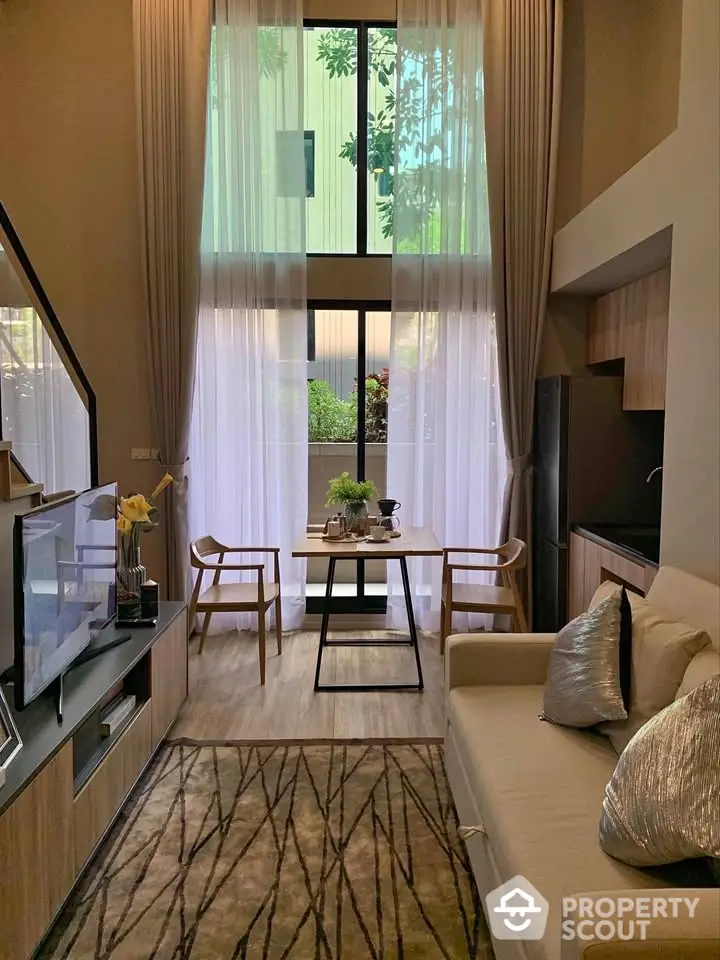 Modern living room with high ceilings and large windows, featuring elegant decor and natural light.