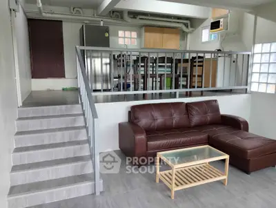 Modern split-level living room with leather sofa and glass coffee table
