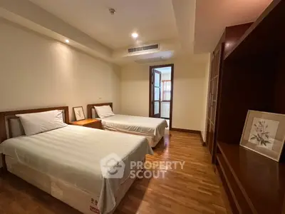 Spacious bedroom with twin beds and wooden flooring in modern apartment