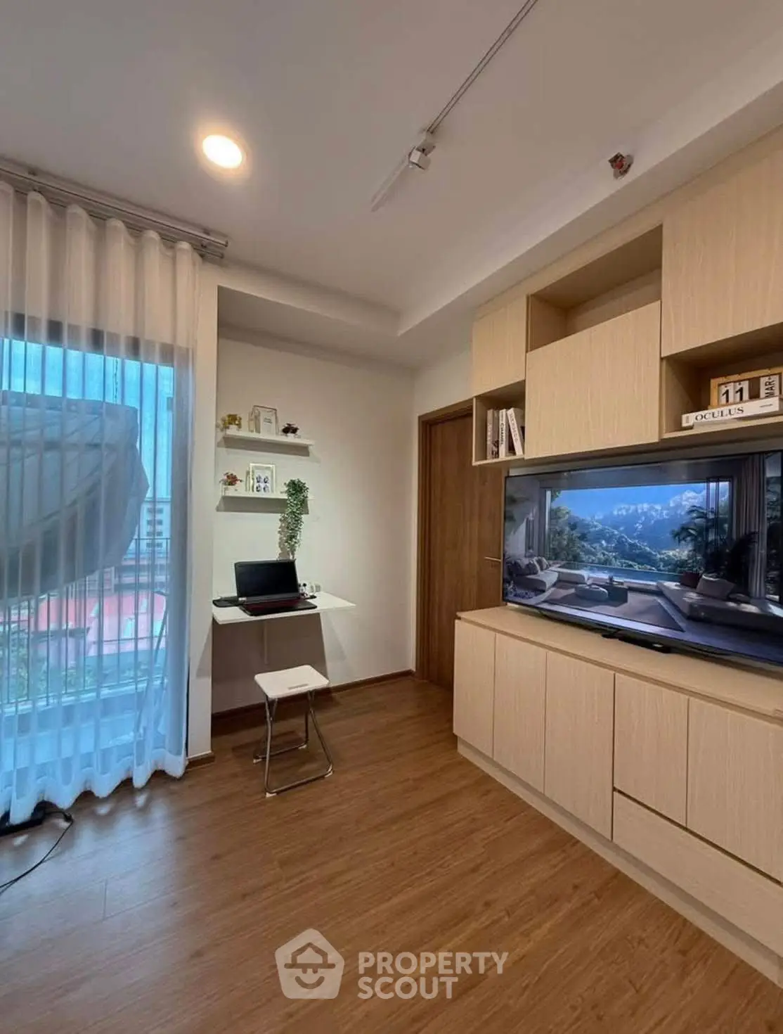Modern living room with built-in TV unit and study nook, featuring wooden flooring and natural light.