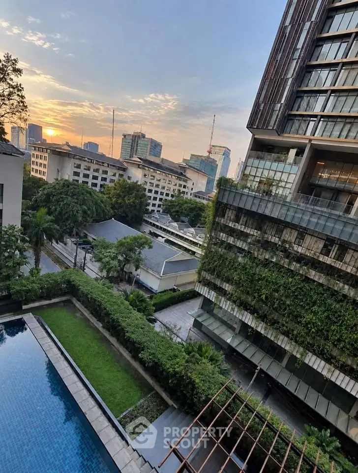 Stunning cityscape view from a modern apartment with lush greenery and a serene pool area.
