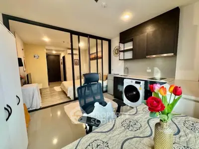 Modern studio apartment with sleek kitchen and cozy living area, featuring stylish decor and natural light.