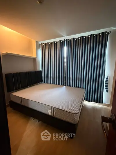 Cozy bedroom with modern design, featuring a comfortable bed and stylish striped curtains.