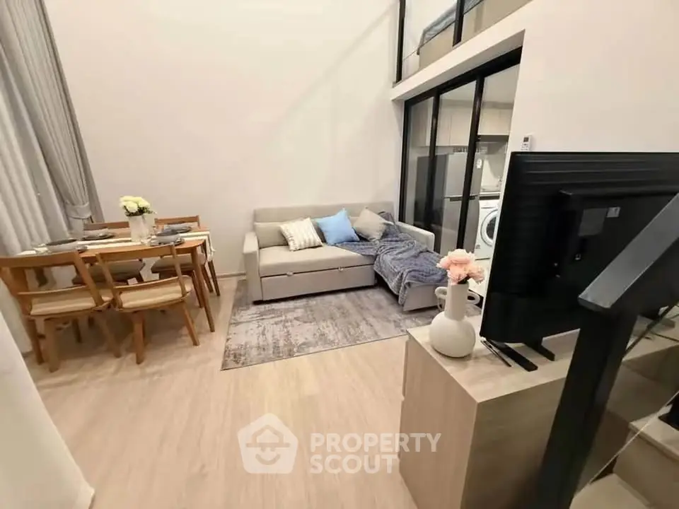 Modern living room with cozy sofa, dining area, and stylish decor in open-plan apartment.