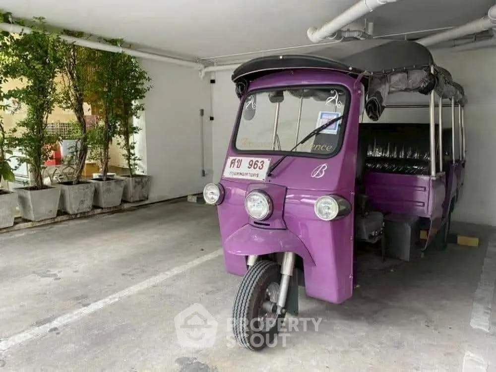 Unique parking space featuring a vibrant purple tuk-tuk in a covered garage area.