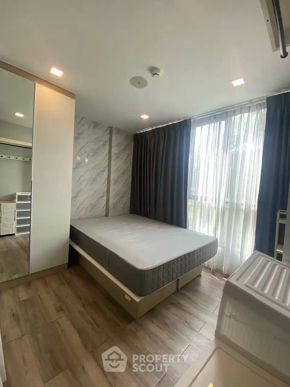 Modern bedroom with large window and stylish decor in a contemporary apartment.