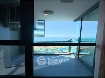 Stunning ocean view from modern apartment balcony with glass railing.