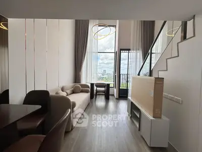 Modern living room with high ceiling and large windows offering stunning city views.