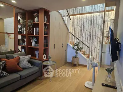 Stylish living room with modern decor and open staircase, perfect for cozy family gatherings.