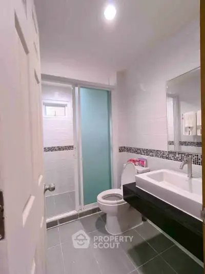Modern bathroom with sleek design, featuring a glass shower enclosure and stylish vanity.