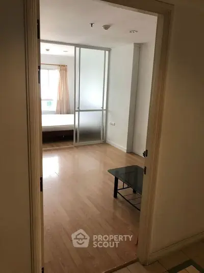 Spacious bedroom with wooden flooring and natural light through large window.