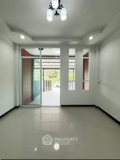 Spacious living room with large windows and modern lighting, offering a bright and airy atmosphere.