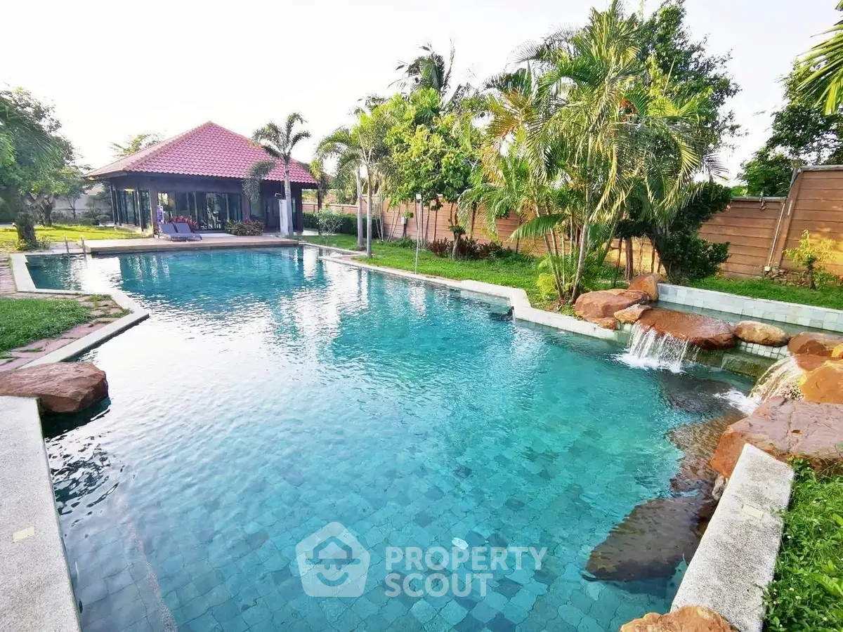 Luxurious outdoor pool with waterfall feature and tropical landscaping