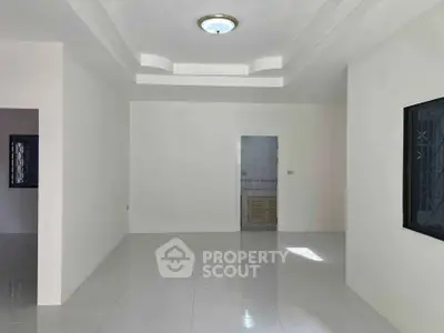 Spacious minimalist living room with modern ceiling design and ample natural light.