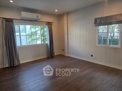 Spacious empty room with hardwood floors and large windows, perfect for customization.