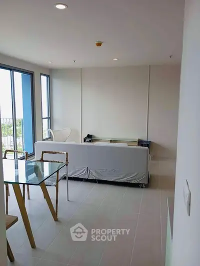 Modern living room with glass table and large windows offering natural light
