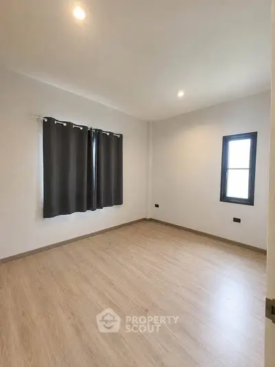 Spacious empty bedroom with wooden flooring and natural light
