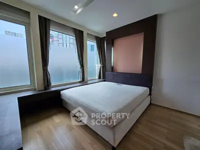 Spacious bedroom with large windows and modern decor in a city apartment.