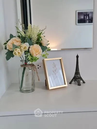 Elegant interior decor with flowers and Eiffel Tower model on a shelf.