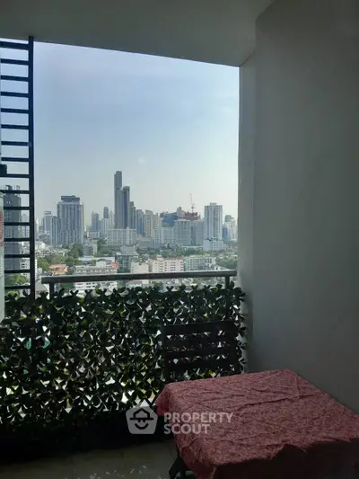 Stunning cityscape view from a cozy balcony with table and chair, perfect for relaxation.