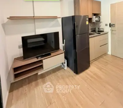 Modern kitchen with sleek appliances and stylish wooden flooring in a contemporary apartment.