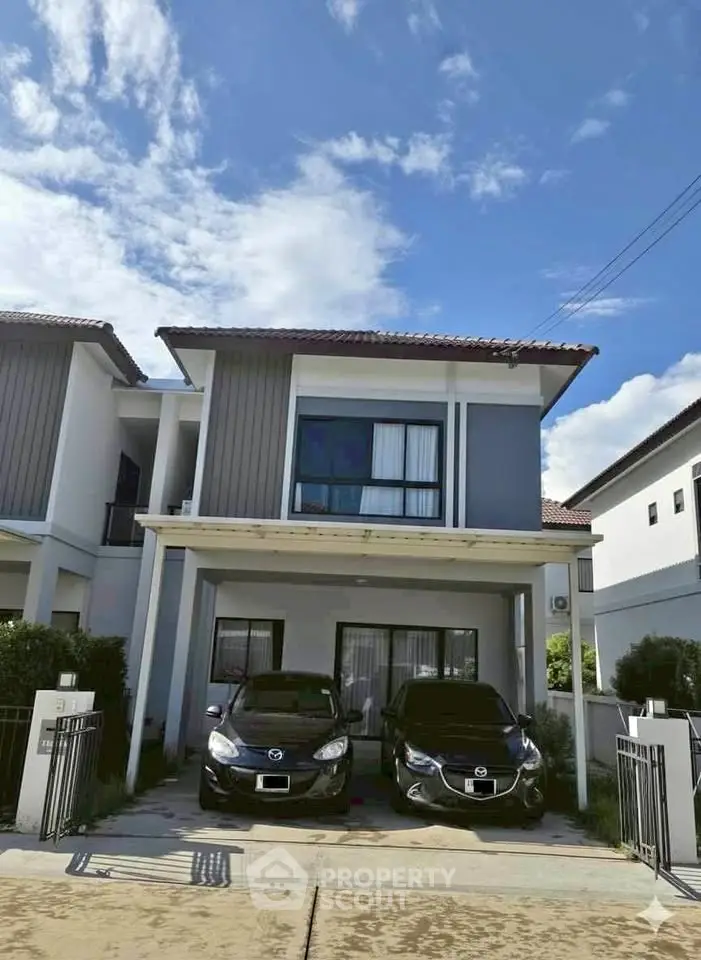Modern two-story house with driveway and two cars parked, showcasing contemporary architecture and clean lines.