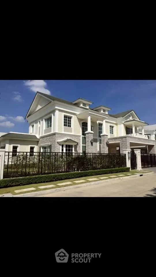 Luxurious two-story house with elegant facade and manicured lawn in a prestigious neighborhood.