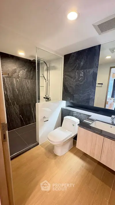 Modern bathroom with sleek black tiles and wooden cabinetry