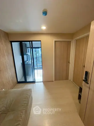 Modern bedroom with wooden flooring and balcony access in a stylish apartment.
