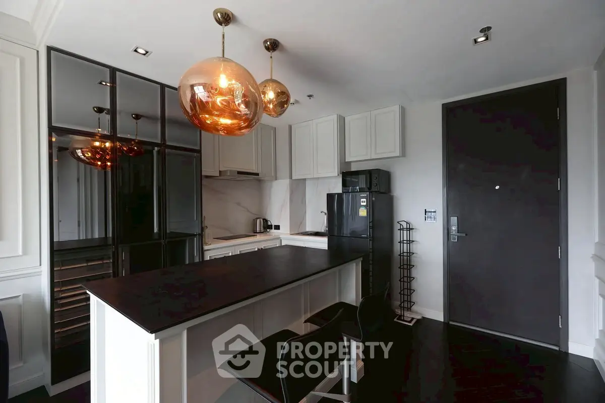 Modern kitchen with sleek black countertops and stylish pendant lights.