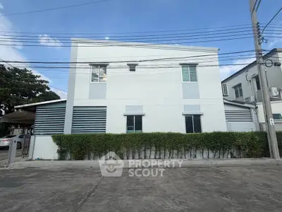 Modern white building exterior with clean lines and lush greenery
