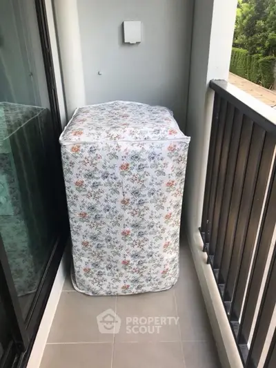 Charming balcony with floral-covered appliance, ideal for cozy outdoor relaxation.
