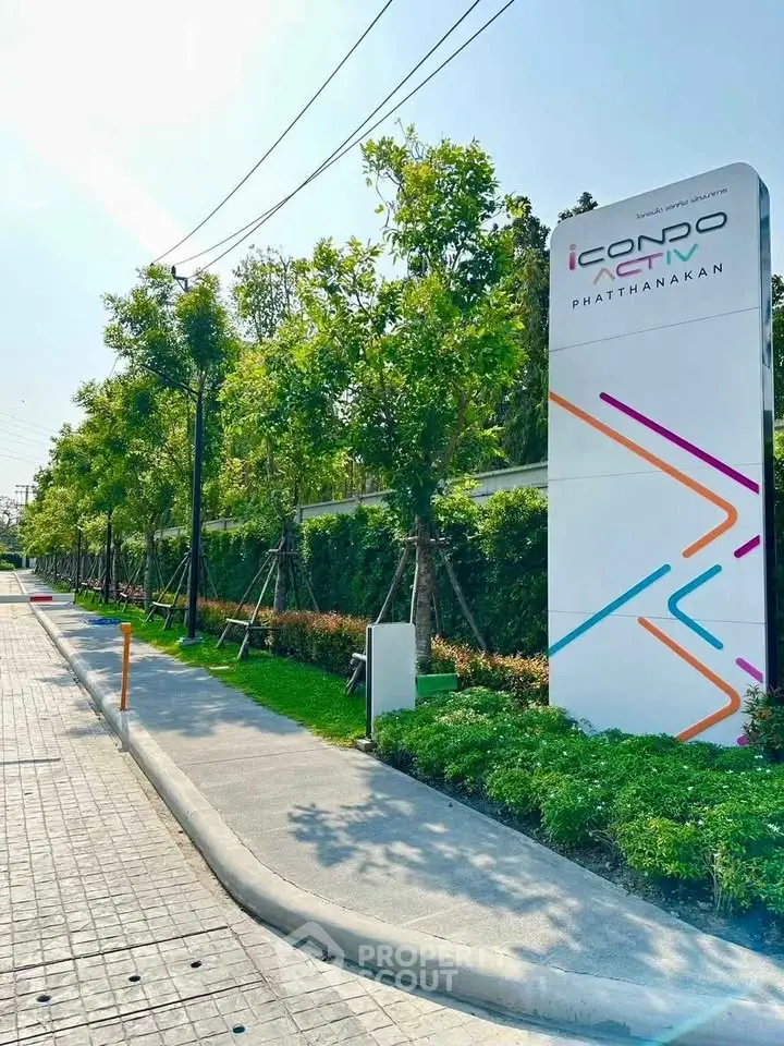 Modern condo entrance with vibrant signage and lush greenery