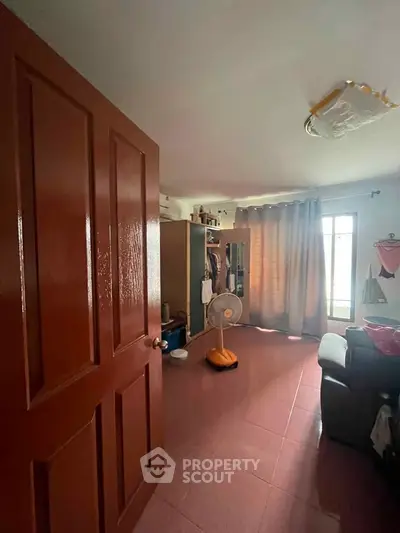 Cozy bedroom with natural light, open wardrobe, and comfortable seating area.