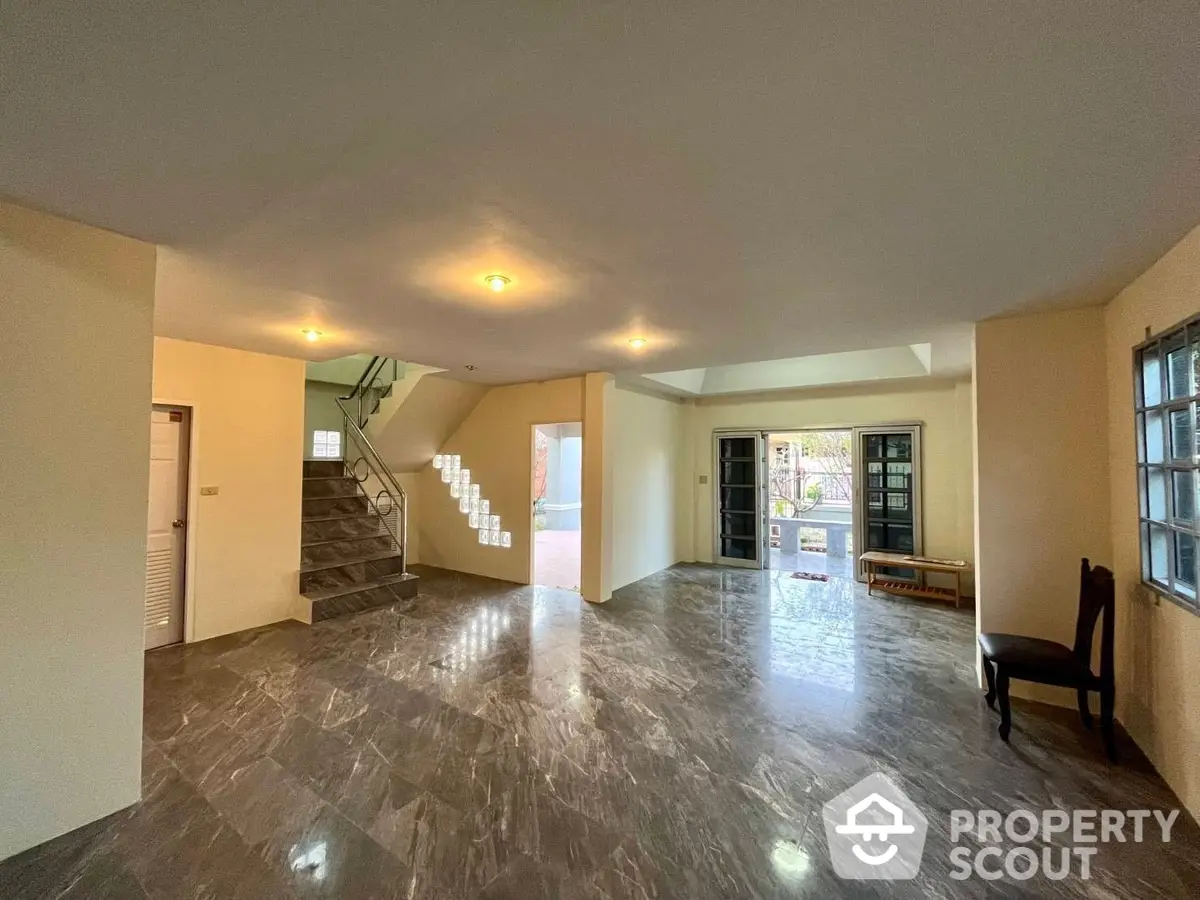 Expansive living space with polished marble floors, elegant staircase, and ample natural light, perfect for luxurious living and entertaining.