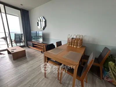 Modern living room with dining area and balcony view, featuring stylish furniture and decor.