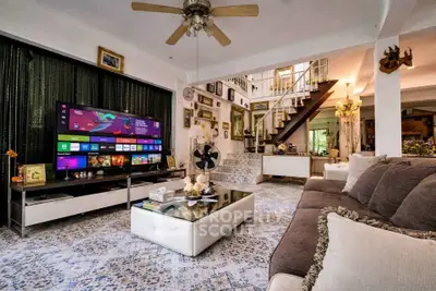 Spacious living room with modern decor and large TV, featuring elegant staircase and cozy seating area.