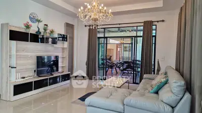Elegant living room with chandelier and modern decor, featuring a spacious layout and stylish furniture.