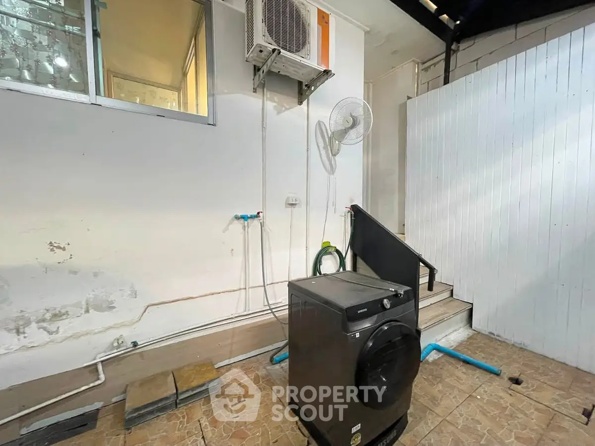 Outdoor laundry area with washing machine and air conditioning unit in a modern home.
