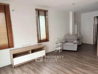 Spacious living room with modern decor and natural light, featuring wooden floors and stylish blinds.