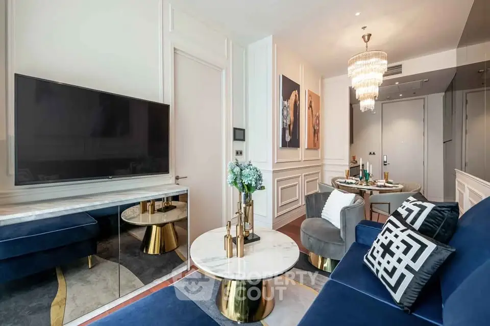 Luxurious living room with elegant decor and modern furnishings, featuring a large TV and stylish chandelier.