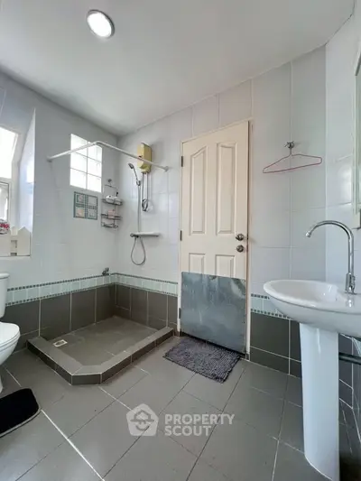 Modern bathroom with shower, sink, and toilet in a bright, tiled space.