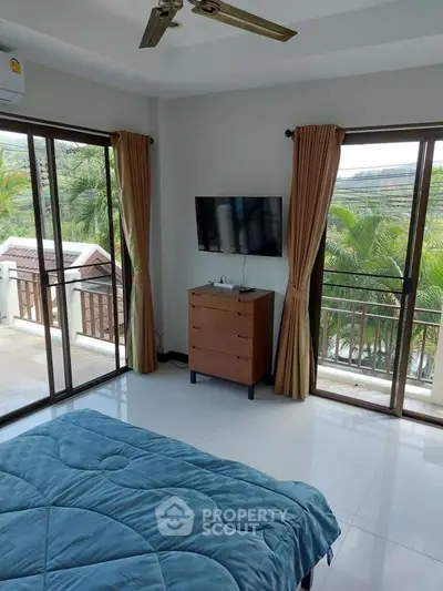 Spacious bedroom with balcony and scenic view, featuring modern decor and natural light.