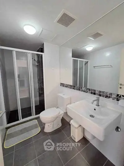 Modern bathroom with glass shower, sleek fixtures, and stylish tile accents.