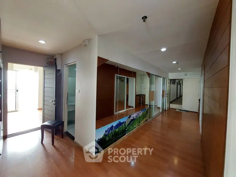 Spacious hallway with wooden flooring and mirrored wall in modern apartment