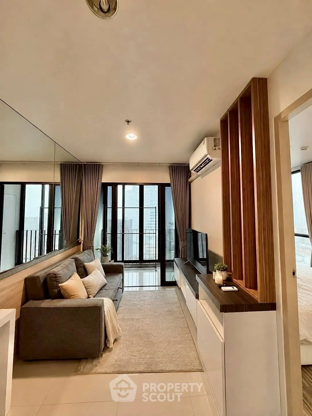 Modern living room with city view, featuring sleek furniture and large windows for natural light.
