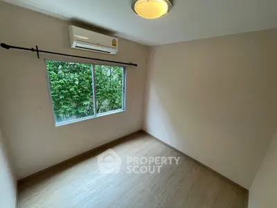 Spacious empty bedroom with large window and air conditioning unit