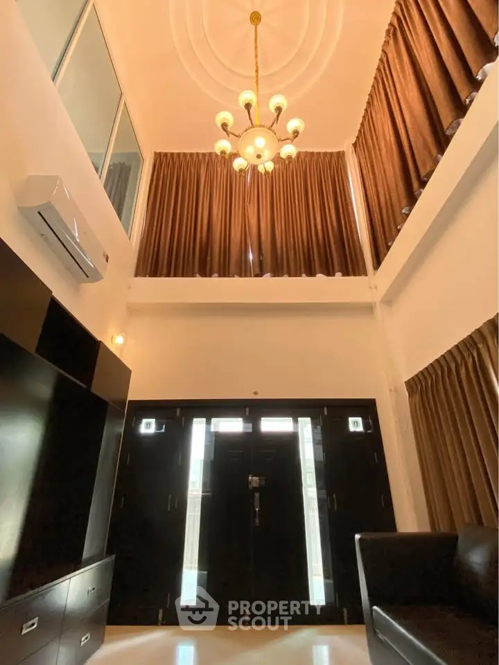 Stunning high-ceiling entrance with elegant chandelier and modern design